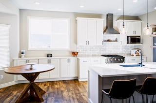 A photograph of a kitchen remodel completed by Homefix in Colorado Springs with white custom built cabinets, marble countertops, and hard wood floors