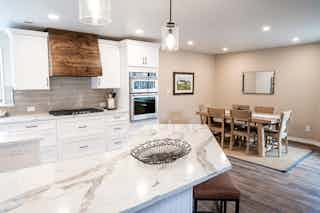 A newly remodeled kitchen with new wooden floors, white countertops, a breakfast bar, and a custom wooden oven hood crafted by Homefix in Colorado Springs