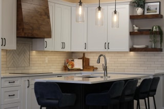 A photograph of a minimal designed kitchen with a wooden oven hood and  marble countertops