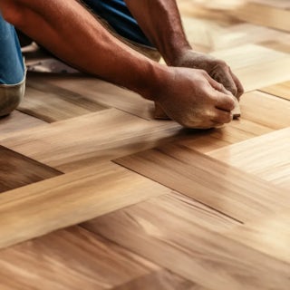 A photograph of a man installing hard wood floors - homefix of Colorado Springs.