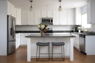 A newly remodeled minimal kitchen with white cupboards and dark marble countertops