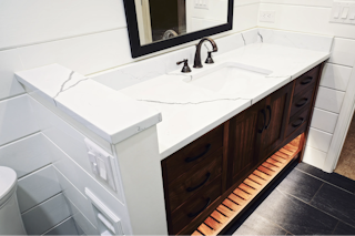 A photograph of a newly installed bathroom counter made of Marble and custom lighting underneath the cabinet in Colorado Springs