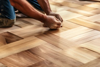 A photograph of a Homefix employee installing new wooden floors
