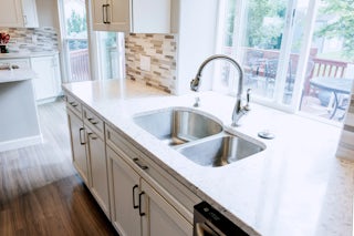 A photo of a newly remodeled kitchen with white countertops and stainless steel sinks in Colorado Springs