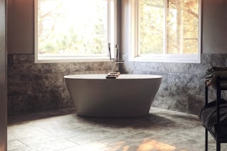 A photograph of a remodeled bathroom with a soaking tub and new grey tile located in Colorado Springs