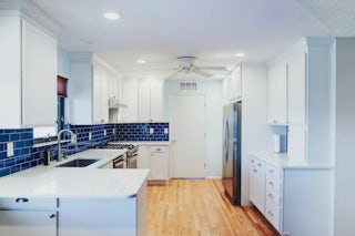 A photograph of a minimal designed kitchen remodel with blue backsplash tile, stainless steel appliances and custom cabinetry, all completed by Homefix in Colorado Springs