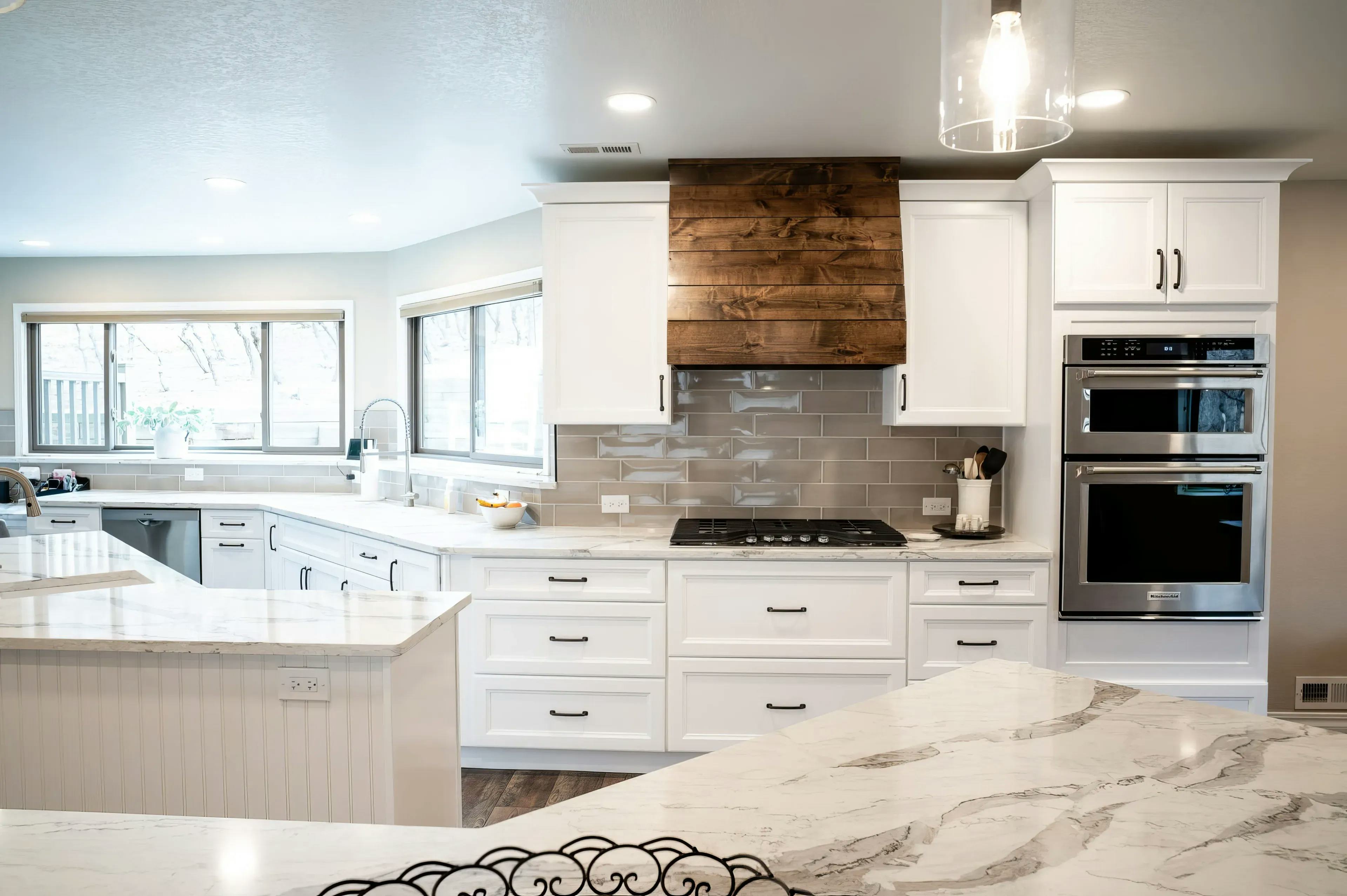 A newly remodeled kitchen with new wooden floors, white countertops, a breakfast bar, and a custom wooden oven hood crafted by Homefix in Colorado Springs